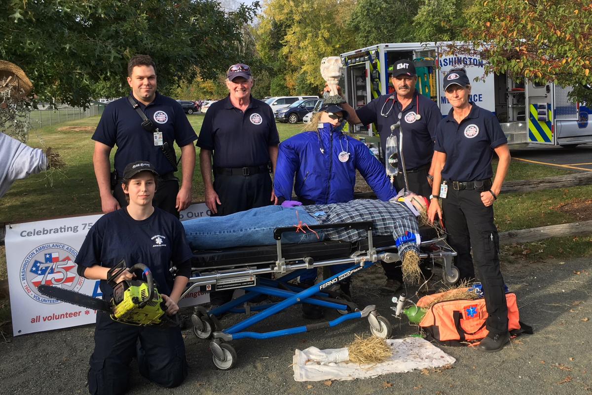 Scarecrow Winner Harvest Fest 2017 - 5 ambulance personnel posing with scarecrow on gurney, ambulance in background right
