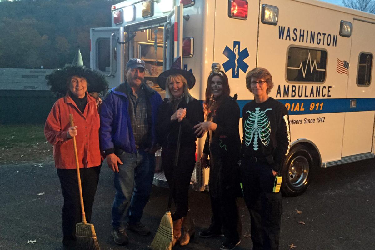 EMS 39, 40, 2, 45, & 44 greeting kids at Trunk-or-Treat 2015 - 5 people in costume standing at rear right of modern ambulance