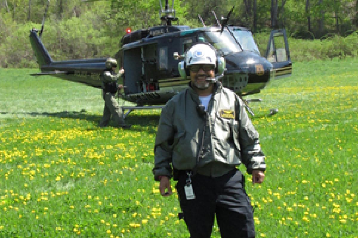 EMS 27 with Eagle One Rescue Chopper - smiling man with helmet standing on grass, helicopter background, man standing at side