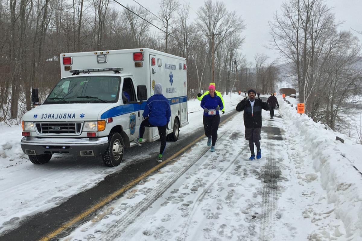 Polar Bear Run standby 2015 - snowy road with modern ambulance on left and 2 peple running past it on right