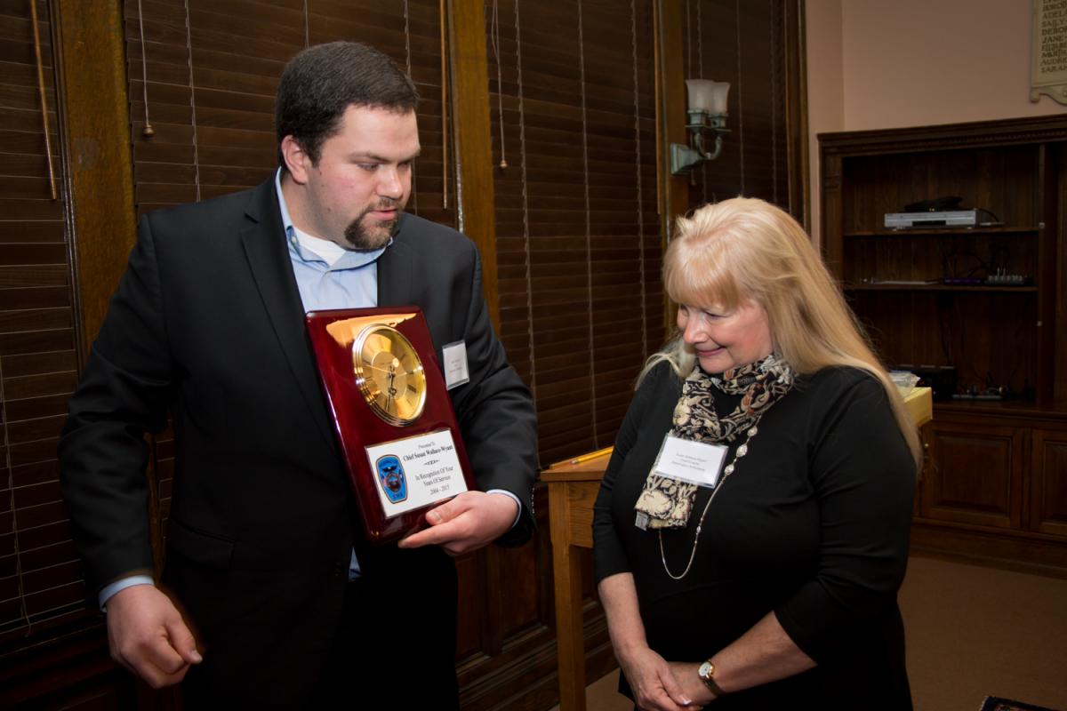 Reception honoring Susie 1/29/2016 - Man showing plaque containing clock to smiling woman