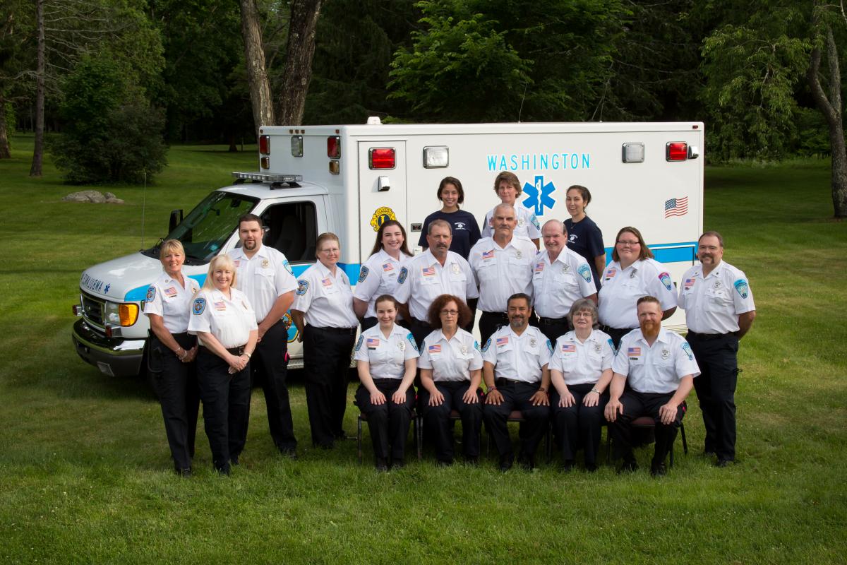 Crew photo taken June 20, 2014 - 2 rows of people (sitting in front, standing behind) in front of modern amnbulance