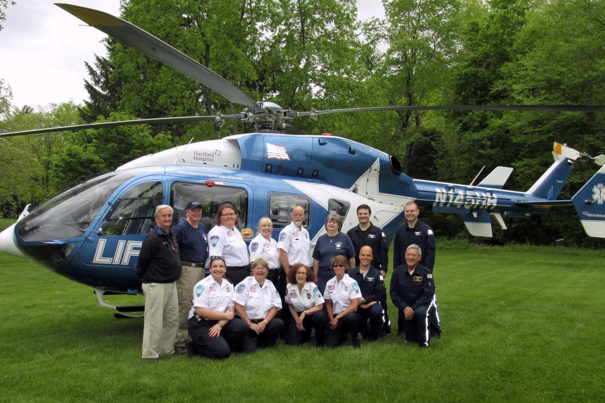 Group photo with LifeStar crew at Open House May 24, 2014 2 rows of people, 1 kneeling,1 standing in front of helicopter